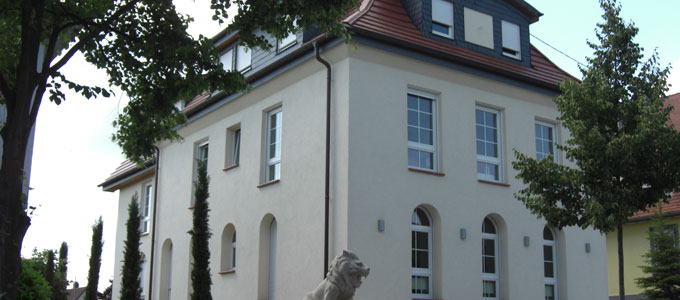 Ein Foto des Gebäudes, in dem sich die Kanzlei befindet. Im Vordergrund ist eine Löwenstatue zu sehen.